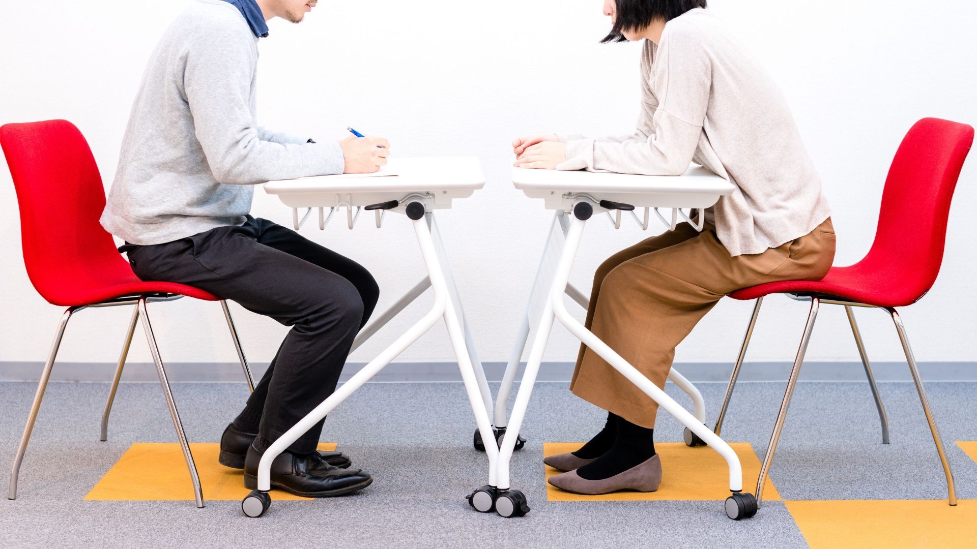 10 Questions You Should Be Prepared to Answer in a College Interview A young adult and a student sit across from each other in interview style stead in rolling chairs and desks — their faces are not visible